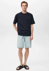 Tricou navy cu mânecă scurtă, asortat cu șorturi din denim de un albastru deschis, completat cu sandale negre. Design minimalist, croială lejeră.