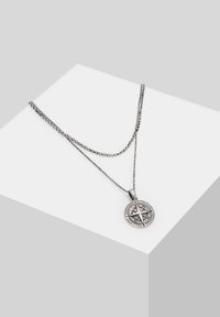 Silberfarbene, geschichtete Halskette mit einem runden Kompass-Anhänger mit filigranen Details und einem strukturierten Kettendesign.
