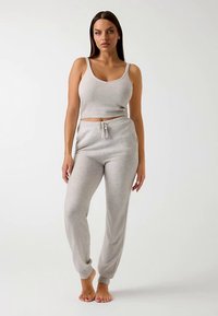 Light gray knitted lounge set including a fitted tank top with a v-neck and matching elastic waistband joggers with cuffs at the ankles.