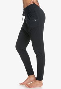 Zwarte, lichte joggingsbroek met een verstelbare tailleband met trekkoord, zijzakken en logo-detail. Glad textuur, slim fit ontwerp.