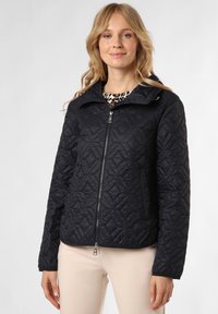 Schwarze gesteppte Jacke mit Reißverschluss vorne, hohem Kragen und Rautenmuster. Mit Seitentaschen und Logodetail am Ärmel.