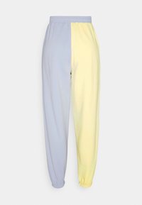 Dvoubarvé teplákové kalhoty v světle modré a pastelově žluté barvě, vyrobené z měkké bavlny, s elastickým pasem a našitými lemy u kotníků.