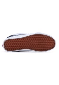 Semelle de chaussure avec motif de gomme brun présentant des motifs de diamants et de cercles, semelle intermédiaire blanche et dessus bleu marine visible sur le côté.