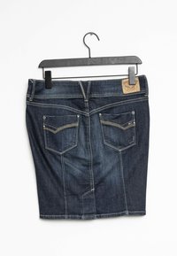 Gonna in denim blu scuro con tasche posteriori e un'etichetta in pelle, appesa a un appendiabiti di plastica nera su uno sfondo bianco.