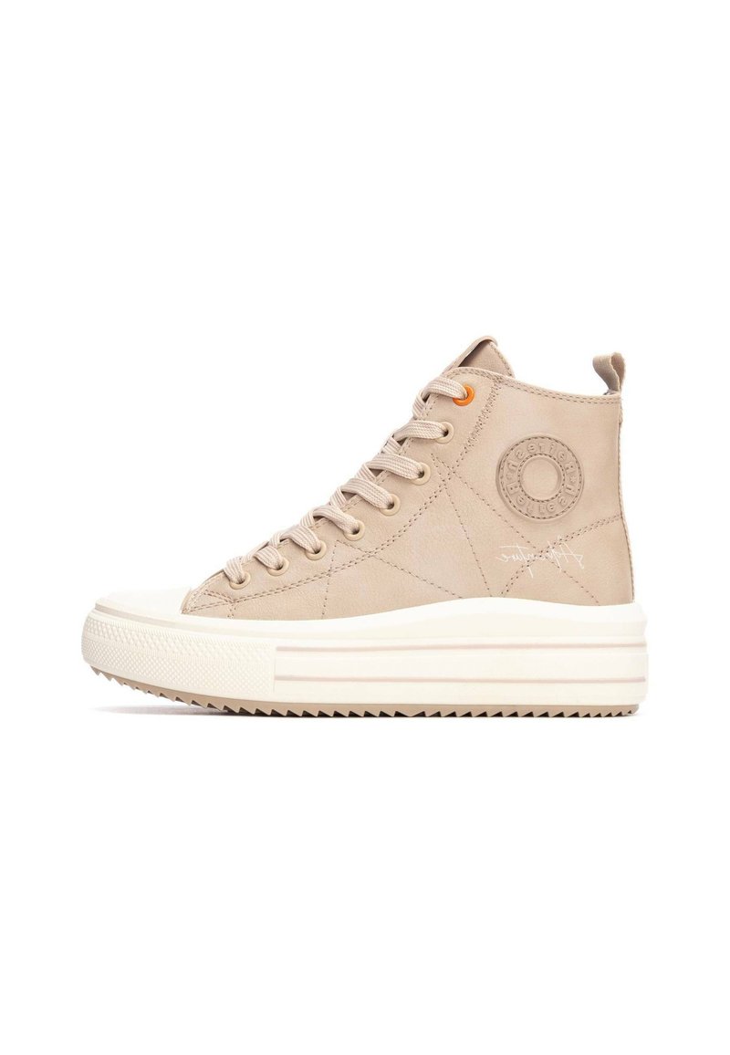 Zapatilla de caña alta beige hecha de tela suave, con una suela de goma blanca, punta redondeada y un detalle de logo circular en el costado.