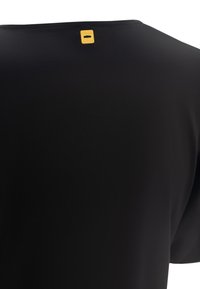 T-shirt nera con una texture liscia, presenta un collo rotondo e un piccolo etichetta gialla del marchio nella zona del collo sul retro.