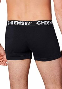 Boxer in cotone nero con elastico bianco in vita che presenta il nome del brand "CHIEMSEY". Aperture delle gambe a taglio dritto e dettagli di cucitura minimi.