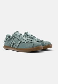 Textilsneaker in hellem Mintgrün mit fransigen Details, flachen Schnürsenkeln und gepolsterten braunen Gummisohlen. Abgerundete Zehenpartie und flaches Design.