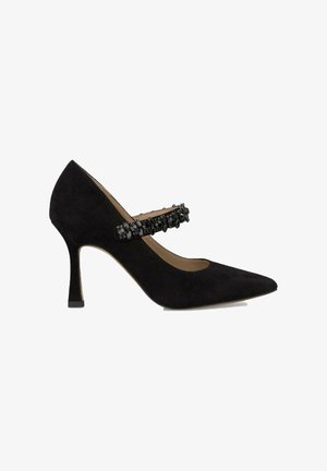 Chaussure à talon haut en suede noir avec un bout pointu et une sangle décorative ornée de perles noires sur le cou-de-pied. Hauteur du talon de 7,5 cm.
