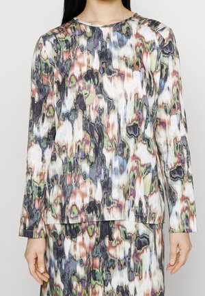 Ensemble haut manches longues et jupe avec un motif abstrait multicolore dans des tons sourds de vert, violet, blanc, noir et marron.