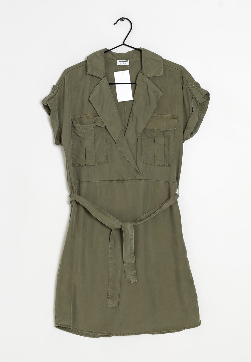 Robe chemise verte olive avec des manches courtes, un col, deux poches avant, et une ceinture assortie. Confectionnée dans un tissu doux et léger.