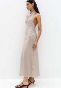 Cremfarbener und brauner gestreifter Halfterkleid mit tailliertem Oberteil und schwingendem Rock. Das Material wirkt leicht und hat eine glatte Textur.