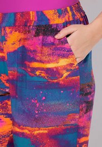 Multicolore stof broek met een abstract patroon in tinten blauw, roze, oranje en zwart, met een elastische tailleband en een zijzak.