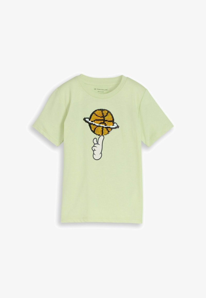 Jasnozielona koszulka z krótkim rękawem z grafiką dłoni kręcącej piłkę do koszykówki zaprojektowaną jako planeta z pierścieniami.