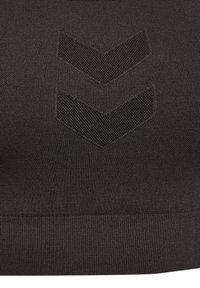 Nahaufnahme eines schwarzen Stoffes mit zwei dunklen Chevron-Mustern, die in das Material über einem gerippten Saum gestrickt sind.