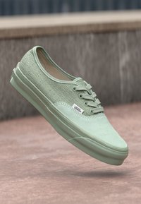 Zapatillas de lona verde menta con un cuerpo texturizado, punta lisa y diseño de cordones. Cuenta con el logo de Vans y suela de goma.
