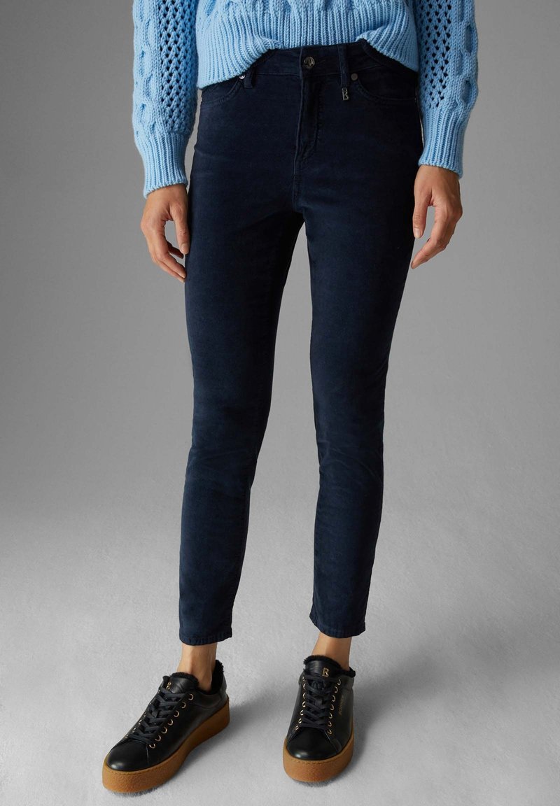 Mörkblå skinny jeans med en slät yta, kombinerat med svarta sneakers med mjuk foder och sula i gummin.