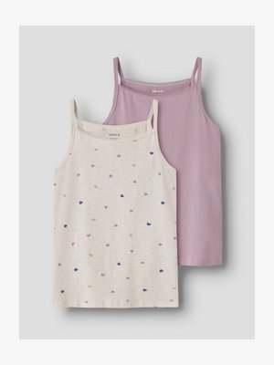 Dos tops sin mangas para niña con tirantes finos, uno lila sólido y otro crema con pequeños patrones de corazones multicolores, colocados sobre una superficie gris.