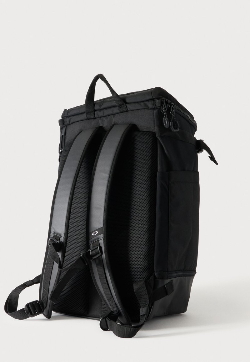 Schwarzer Rucksack mit gepolsterten Schultergurten, mehreren Reißverschlussfächern und einem oberen Griff, vor einem einfarbigen hellen Hintergrund gezeigt.