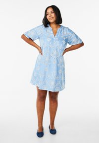 Robe en coton bleue avec un décolleté en V et des manches courtes, ornée de motifs de broderie circulaire blancs et d'œillets découpés sur l'ensemble.
