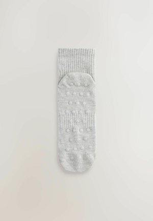 Lysegrå sok med ribbet kant, med teksturerede grebspunkter på sålen for ekstra trækkraft og stabilitet.