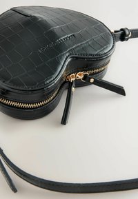 Borsa a forma di cuore in pelle nera con effetto coccodrillo, con zip e dettagli in tono oro, dotata di una tracolla staccabile e finitura testurizzata.
