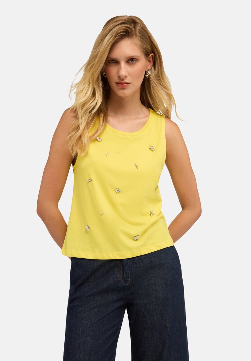Top giallo senza maniche in cotone, con decorazioni ornamentali sparse sulla parte anteriore, scollo rotondo e vestibilità rilassata.