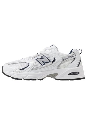 Weißer New Balance Laufschuh mit Mesh-Einsätzen, Navy-Logo und sichtbarer ABZORB-Dämpfung in der Sohle, Seitenansicht.
