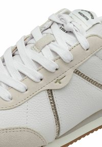 Sneaker in pelle bianca con accenti in suede grigio chiaro, lacci bianchi piatti e un dettaglio decorativo con zip sul lato. Superficie testurizzata.