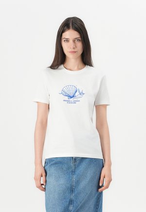 Hvit bomull T-skjorte med korte ermer, med et blått skjellgrafikk og krøllete tekst "Seashell Seeker Siden 1996" på forsiden.