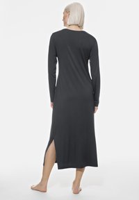 Grijze maxi-jurk met lange mouwen, een ronde halslijn en zijsplitten, gemaakt van een zachte stof, met een ontspannen pasvorm en een minimalistisch ontwerp.