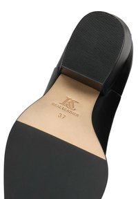 Svart lädersko sula med ribbad textur, stämplad märkning "KS REAL LEATHER" och storlek "37" på en beige innersula. Slät yta.