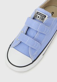 Ανοιχτό μπλε αθλητικό παπούτσι Converse All Star με δύο λο υράκια με βέλκρο και λευκή λαστιχένια μύτη σε λευκό φόντο.