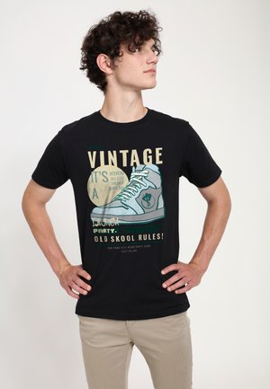 T-shirt in cotone nero con una grafica di una sneaker e testo. Design a girocollo, maniche corte e vestibilità comoda. Testo in vari colori.