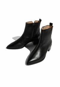 Botas de cuero negro hasta el tobillo con puntas afiladas, tacones bajos tipo bloque y cremalleras laterales. Textura suave y diseño minimalista.