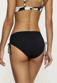 Czarny dół bikini z regulowanymi sznureczkami po bokach, posiadający gładką teksturę i średnie pokrycie. Akcenty kontrastowego materiału na górze.