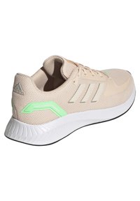 Scarpe atletiche beige con superiore in rete, accenti bianchi riflettenti, dettagli verdi sui lati e suola in gomma bianca texturizzata.
