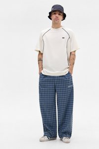 T-shirt i creme med sorte kantbånd, parret med blåternede pyjamabukser. Har en afslappet pasform og hvide sneakers. En bøttehat fuldender looket.