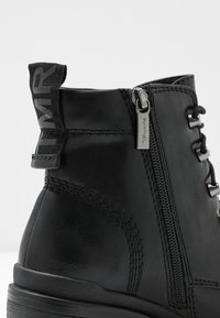 Musta nahkakenkä, jossa on teksturoitu pinta, sivuvetoketju, nyöritys edessä ja vetotappi, jossa lukee "MR." Musta kumipohja.