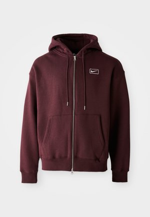 Maroon zip-up hoodie made of cotton blend, featuring a front pocket, drawstring hood, and a small white logo on the chest.