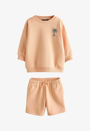Set van sweatstof in perzikkleur bestaande uit een top en shorts. De top heeft een ronde hals, verlaagde schouders en groene palmbomenborduursels. De shorts hebben een elastische tailleband.
