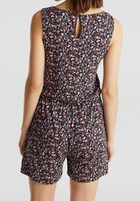 Combinaison sans manches à fleurs avec des fleurs roses et bleues sur un fond noir, dotée d'un détail en trou de serrure au dos et d'une taille élastique.