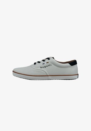 White perforated shoes with black laces and accents. Rubber sole with brown edging and logo on the side. Smooth texture, sporty design.