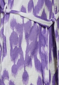 Lila- und weiß gemustertes Stoff, mit einer Leinenstruktur; zeigt ein abstraktes Design und eine gebundene Gürtel-Detail für den Verschluss.