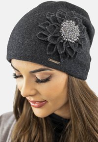 Berretto a maglia nero con un accento di fiore testurizzato che presenta perline trasparenti al centro. Progettato per una vestibilità aderente. Branding sottile sul lato.