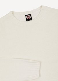 Suéter de punto color crema con cuello redondo y puños acanalados. Presenta una etiqueta con el logo en la zona del cuello. Textura suave.