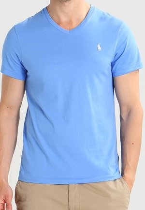 Jasnoniebieska koszulka z krótkim rękawem i dekoltem w serek, wykonana z miękkiego materiału, z małym białym logo na piersi. Klasyczny krój, gładka tekstura.