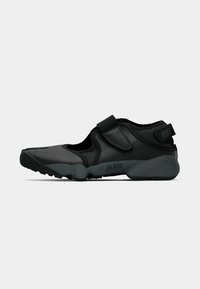 Čierne tenisky Nike s textúrovaným zvrškom, suchým zipsom a odpruženou podrážkou s označením "AIR" na boku. Nízky profil.