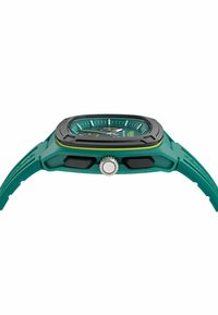 Zaļš silikona pulkstenis ar kvadrātveida ciparnīcu, melnu rāmīti un kontrastējošām dzeltenām akcentiem. Tam ir struktūrēta siksna un sudraba kronis.