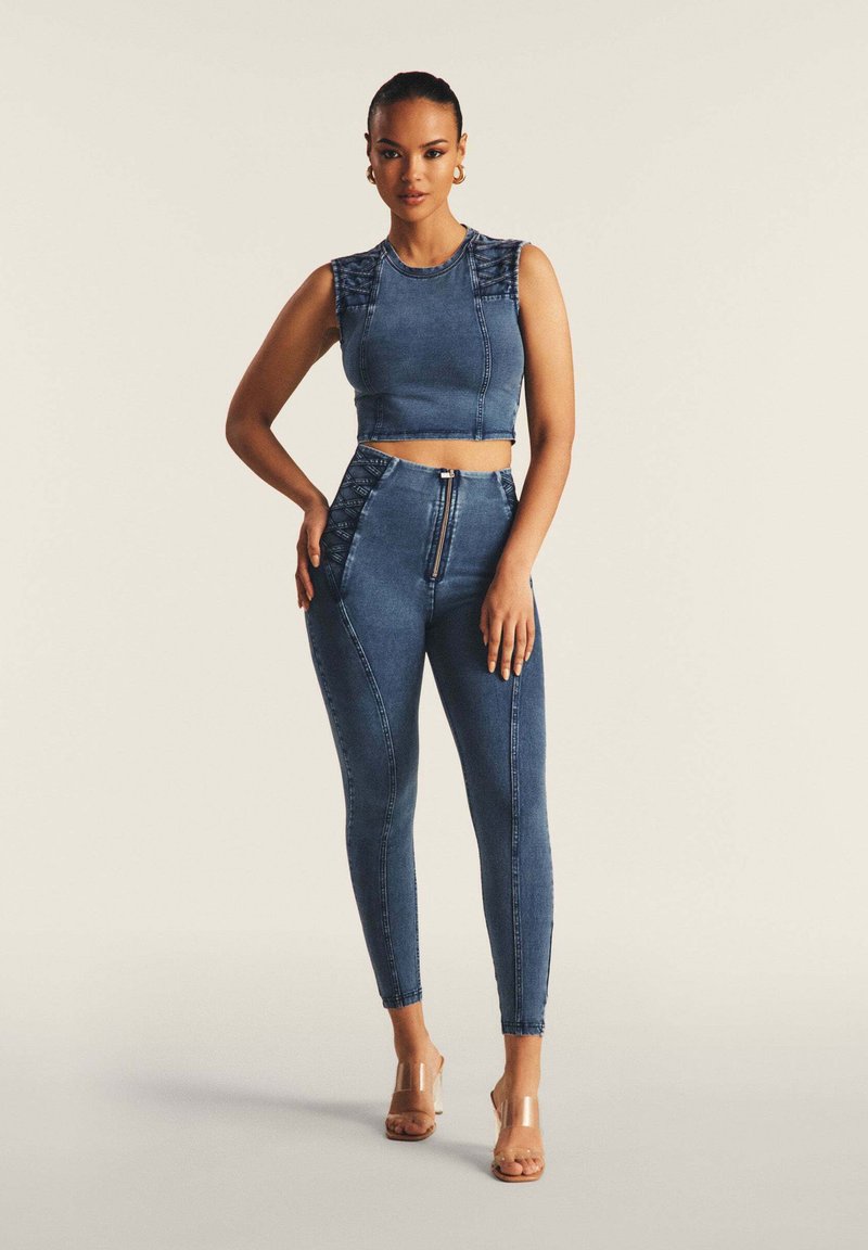 Denim crop top dengan aksen bahu berkerut dan celana jeans high-waisted yang dilengkapi penutup ritsleting serta jahitan kaki dalam warna biru sedang.